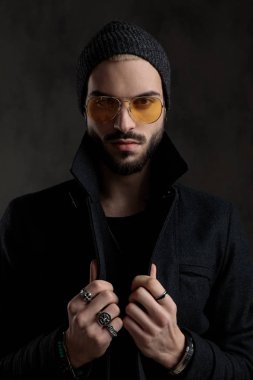 Çekici erkek ceketi gri bir arka plan üzerinde yaka düz ön kameraya bakarken ayarlama