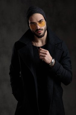 Çekici bir adam onun kolye gri bir arka plan üzerinde onun cebinde tek elle ayarlama