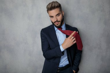 Kravatını gri arka plan üzerinde oynamaktan serin genç işadamı