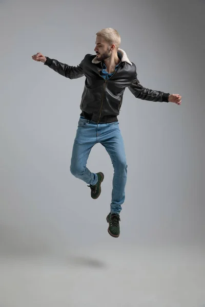 Hombre Chaqueta Cuero Jeans Saltando Sobre Fondo Gris —  Fotos de Stock