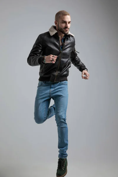 Man Leren Jas Jeans Sprongen Kijkt Weg Grijze Achtergrond — Stockfoto