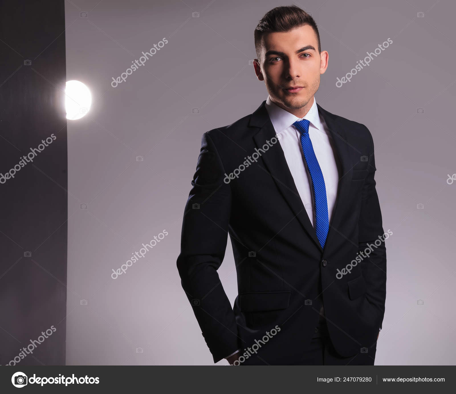 ファッションをされている彼のポケットに手を立っている青いネクタイと黒スーツの男 ストック写真 C Feedough