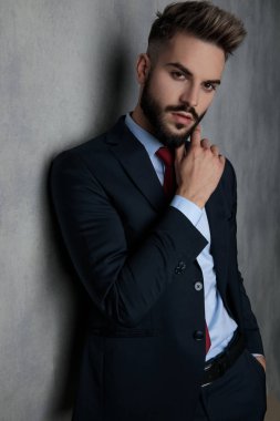 seksi genç işadamı düşünme, gri duvara yaslanmış