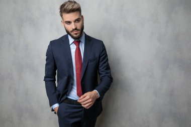 serin genç işadamı gri studio duvara cebinde el ile yürüyor
