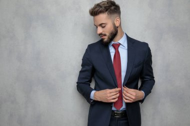 genç işadamı ceketini unbuttoning gülümsüyor ve stüdyo duvara tepeden bakıyor