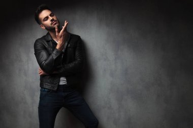 deri ceketli kibirli seksi genç adamı studio poz bir tarafına işaret