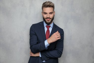 gülümseyen genç işadamı duran gri duvara düşünme