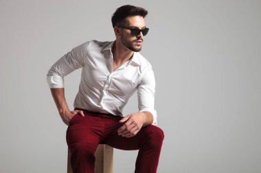 çekici bir adam onun cep ve ağız gri arka plan üzerine açık el ile poz veriyor