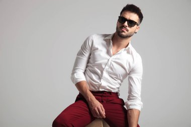 çekici bir adam ise tarafında yaslanmış ve gri arka plan üzerinde güneş gözlüğü takıyor ciddi bir görünüm verir