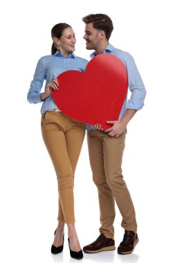 Birbirimizi ve beyaz arka plan üzerinde büyük kırmızı kalp tutarken öpmeye hazır bakarak aşk rahat Çift