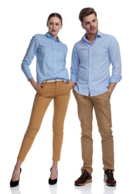 Elleri ceplerinde yan, kamerayı beyaz arka plan üzerinde uzak isteyen ile rahat Çift