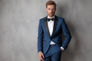 Zarif adam cebinde bir ışık gri arka plan üzerinde kameraya bakarak şapkasını tutarak