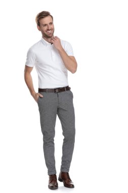 yaka ayarlama ve uzak bir tarafı beyaz arka plan üzerinde seyir genç casual adam gülüyor