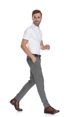 Smart casual adam gülümseyerek yürür ve geri omzunun üzerinden beyaz arka plan üzerinde görünüyor