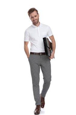 rahat gülümseyen smart casual adam bavul holding beyaz arka plan üzerinde yürüyor