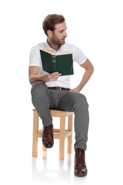 bir sandalyede oturan adam bir kitap tutan ve tarafına beyaz arka plan üzerinde görünüyor