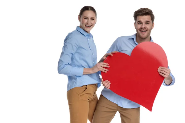 Riendo Joven Pareja Compartiendo Gran Corazón Rojo Sobre Fondo Blanco — Foto de Stock