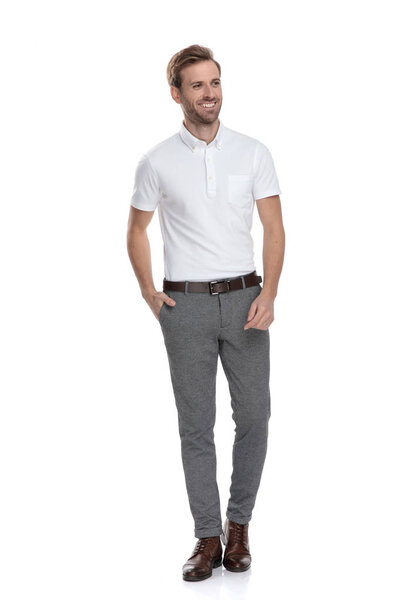 расслабленной улыбкой умный случайный человек смотрит в сторону, стоя на белом фоне
