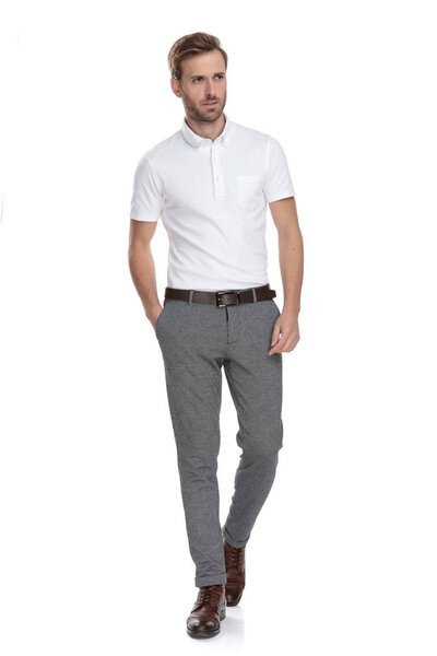 молодой умный случайный человек ходит с рукой в кармане и смотрит в сторону на белом фоне
