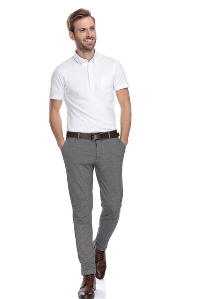 Любопытный человек с руками в карманах прогулки и смотрит в сторону на белом фоне
