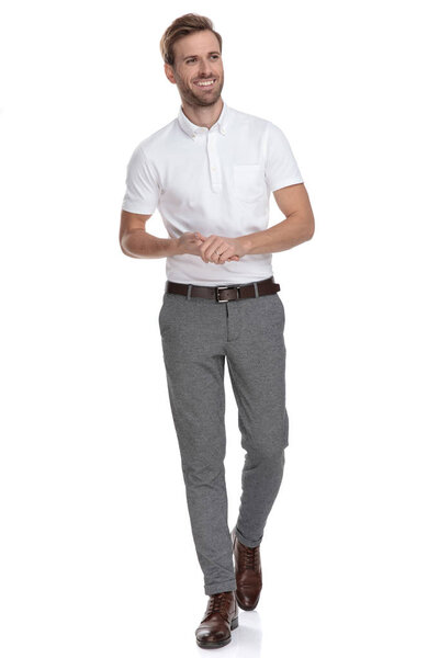 Смеющийся молодой случайный человек держит ладони вместе идет и смотрит в сторону на белом фоне
