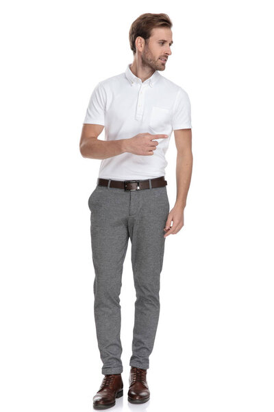 молодой умный случайный мужчина указывая пальцем в сторону, глядя в сторону от камеры на белом фоне
