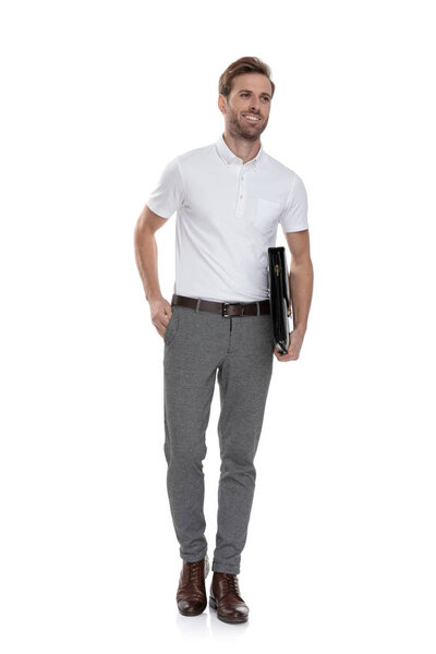 улыбающийся молодой случайный мужчина с портфелем и одной рукой в кармане смотрит в сторону на белом фоне
