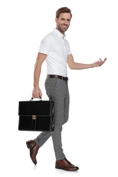 スーツケースと歓迎や白い背景の上を指して笑いスマート カジュアルな男の側面図 — ストック写真