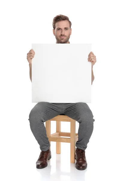 Zittende Casual Man Houdt Een Leeg Bord Witte Achtergrond — Stockfoto