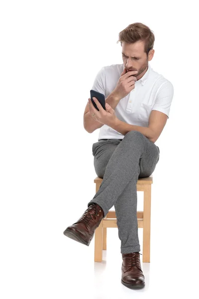 Homem Sentado Parece Preocupado Ler Seu Telefone Fundo Branco — Fotografia de Stock