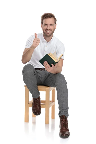 Lächelnder Sitzender Mann Liest Ein Buch Und Macht Das Zeichen — Stockfoto