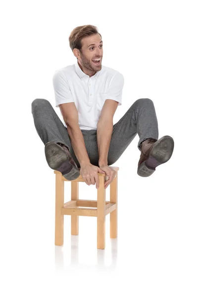Louco Casual Homem Sentado Segura Pernas Enquanto Olha Para Lado — Fotografia de Stock