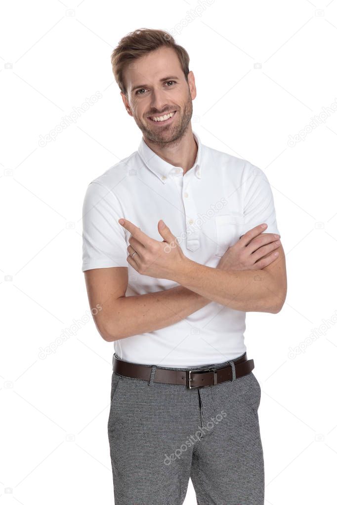 smiling casual man with hands crossed pointing to side on white background 