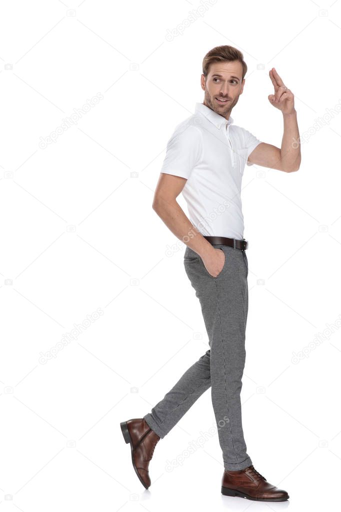 happy young smart casual man walks and greets while looks back over his shoulder on white background