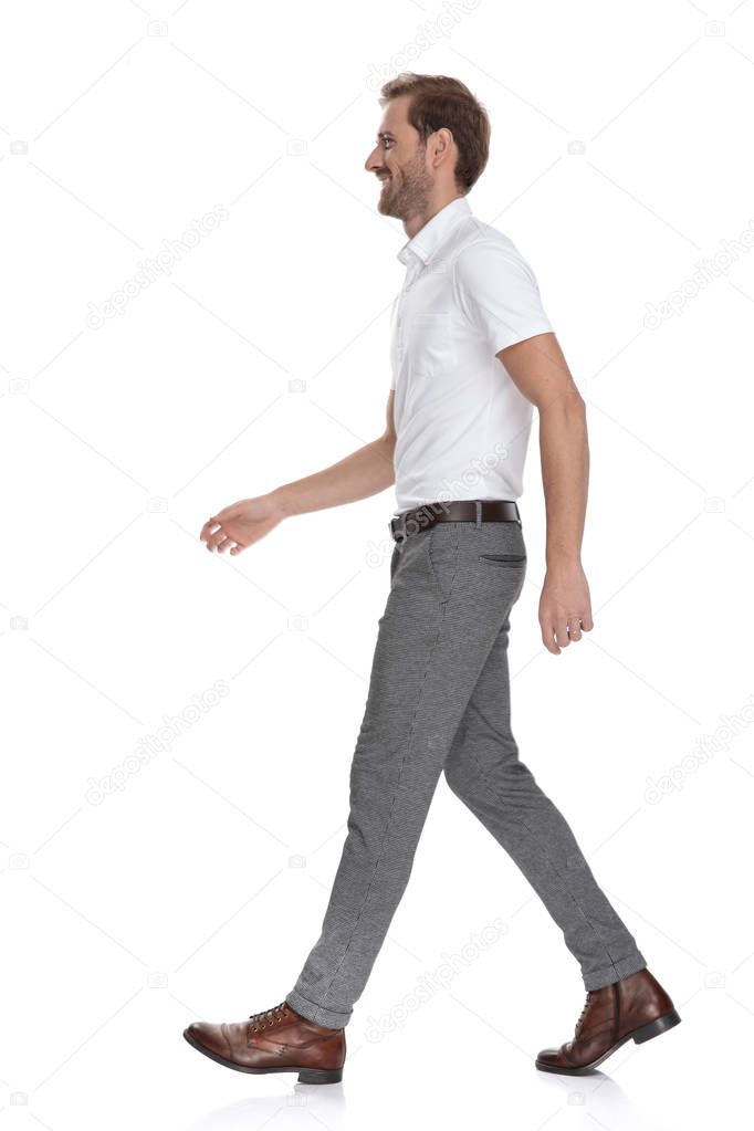 side view of a happy young man walking forward on white background