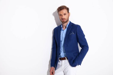 çekici bir adam el ile cebinde durur.