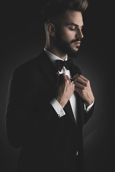 man in tuxedo adjusting his collar with eyes closed