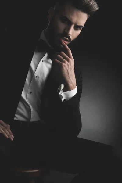 Man in tuxedo sitting on chair with finger at lips — Stock Photo, Image