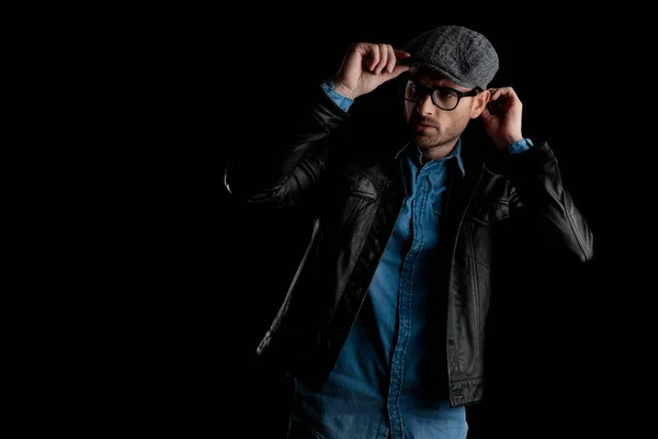 Frown man with eyeglasses adjusting his cap with both hands — Stock Photo, Image