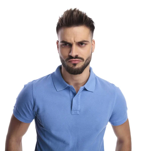 Joven hombre inmaduro usando un polo azul claro frunciendo el ceño —  Fotos de Stock