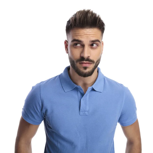 Gondolkodó fiatal ember visel egy világos kék póló néz felfelé a — Stock Fotó
