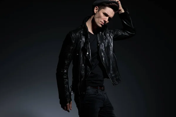 Angry fashion man in leather jacket holding his hat — Stock Photo, Image