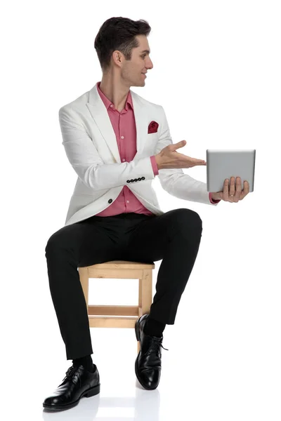 Sentado joven hombre de negocios recomendando tableta a su lado — Foto de Stock