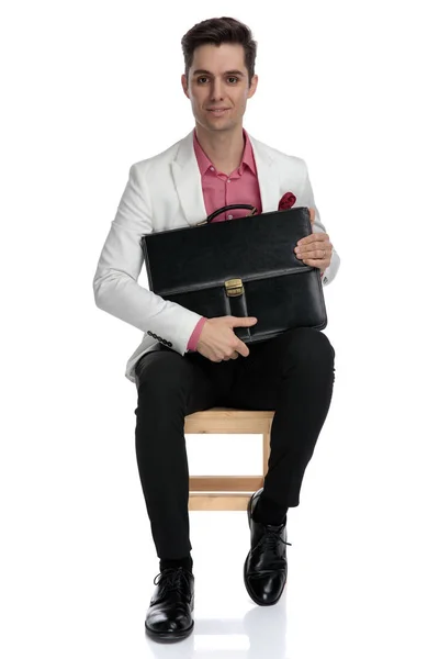 Χαμογελαστός νεαρός επιχειρηματίας που κρατάτε βαλίτσα κάθεται — Φωτογραφία Αρχείου