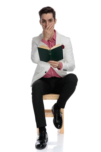 Schockierter eleganter Mann sitzt und liest ein spannendes Buch — Stockfoto