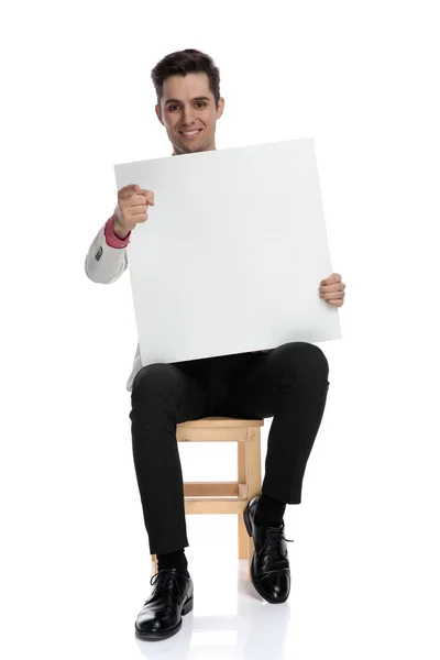 Sitzender eleganter Mann mit leerem Brett zeigt mit dem Finger — Stockfoto