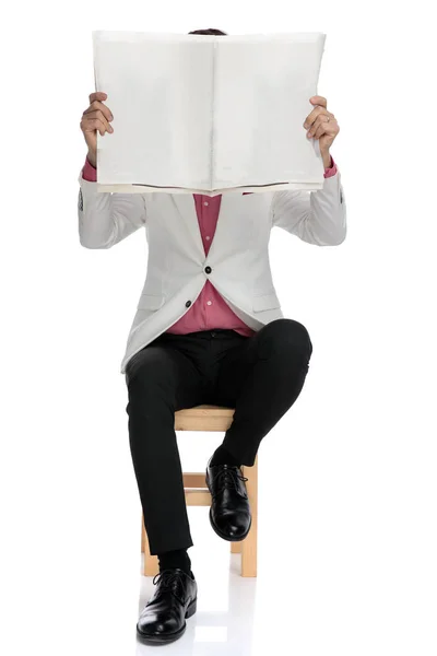 Sentado homem elegante segurando papel sobre seu rosto — Fotografia de Stock