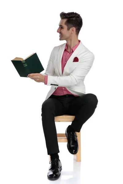 Oturma ve onun kitabı tarafa göstererek mutlu zarif adam — Stok fotoğraf