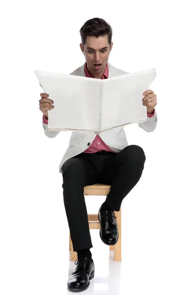 Chocado homem elegante sentado e lendo jornal com boca ope — Fotografia de Stock