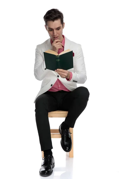 Сидящий элегантный мужчина очарован своим интересным романом — стоковое фото